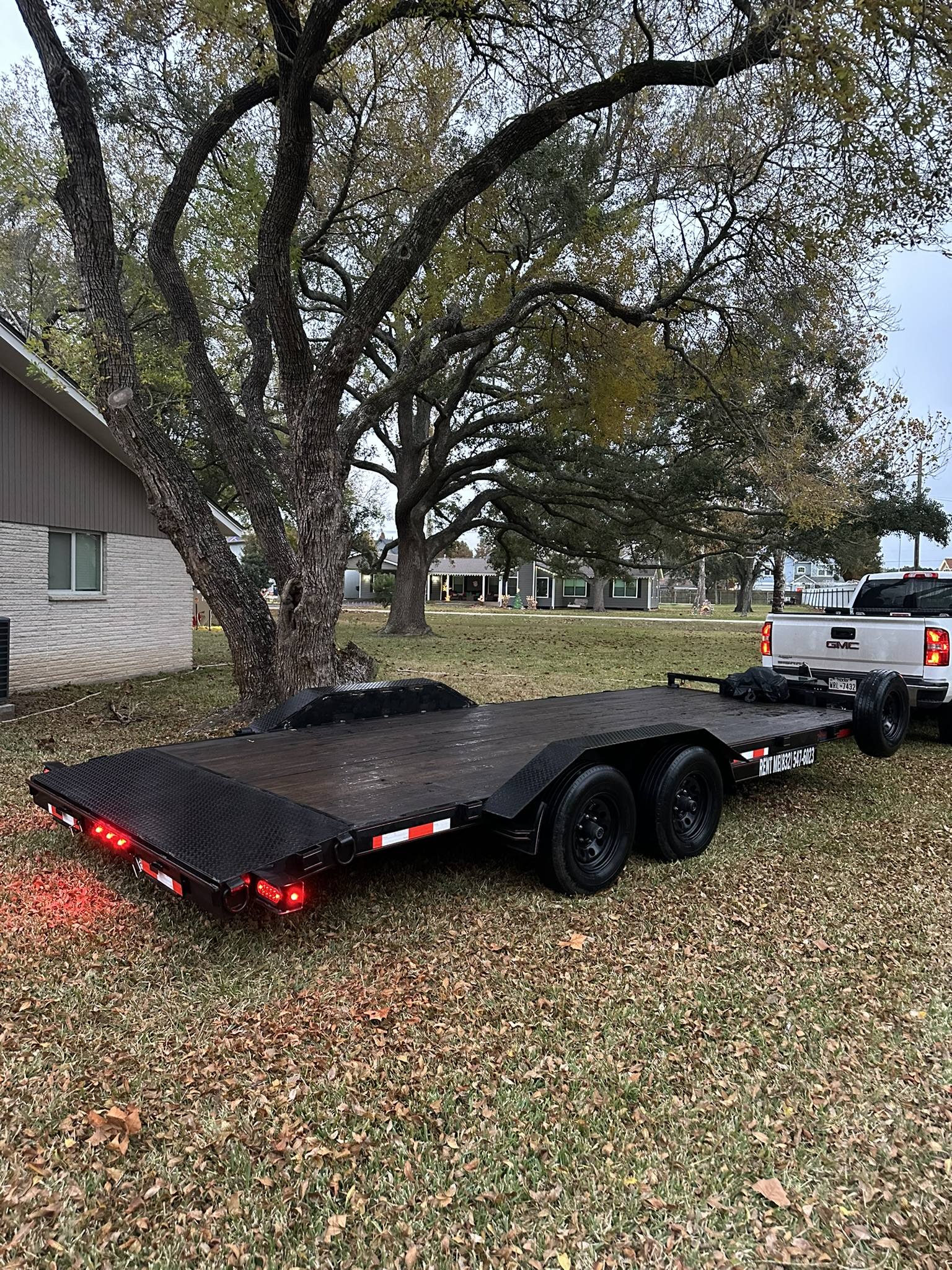 Black flatbed car hauler trailer with red LED lights